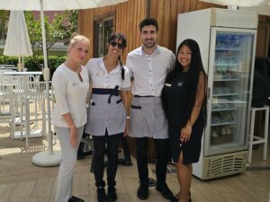 Due stagiste stanno scattando una foto con i loro colleghi di lavoro durante il loro tirocinio in hotel all'estero.