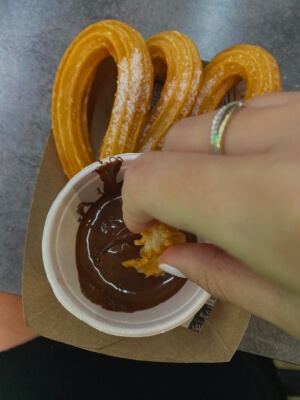 Ein Hotelpraktikant genießt einen traditionellen spanischen Snack, Churros, während seines Praktikums in Spanien.