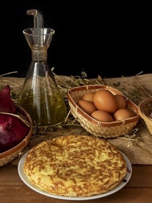 Un stagiaire en hôtellerie dégustant une tortilla espagnole traditionnelle dans un restaurant local en Espagne pendant son stage.